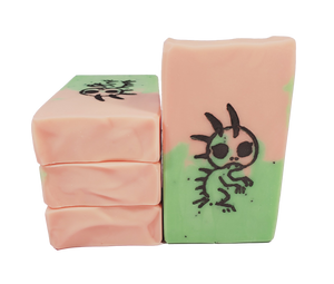 Four bars of Chupacabra soap, which are peach and lime colored with poppy seeds. A lizard-like creature is stamped on the bar.