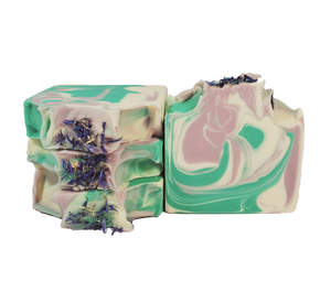 Four bars of Nymph soap, with white, purple, and turquoise swirls and blue cornflower petals on top.