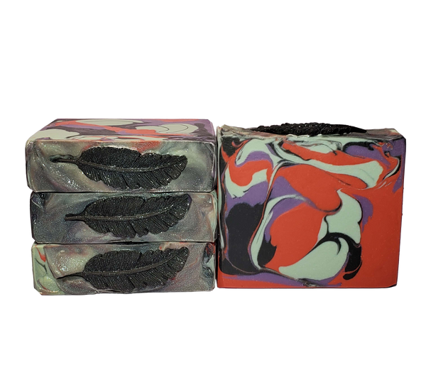 Four bars of The Morrigan soap. Each bar contains red, light green, purple, and black swirls and is topped with a black soap feather and glitter.