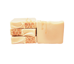 Four bars of Queen Bee soap. Each bar is pale yellow. There is a honeycomb pattern on half of the top of each bar, with a golden soap drizzle resembling honey that drips across the honeycomb pattern and down the front of each bar.