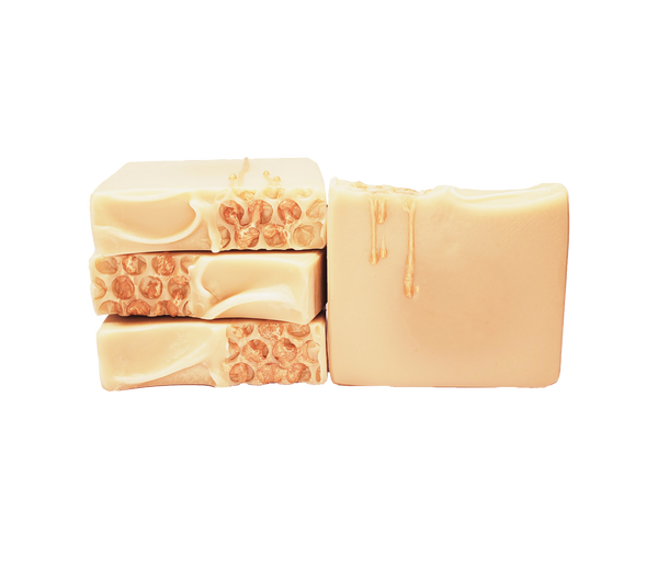 Four bars of Queen Bee soap. Each bar is pale yellow. There is a honeycomb pattern on half of the top of each bar, with a golden soap drizzle resembling honey that drips across the honeycomb pattern and down the front of each bar.