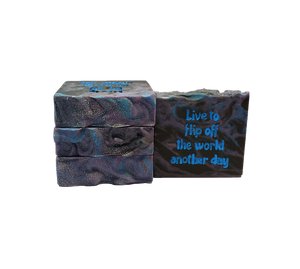 Four bars of Space Mom soap. Each bar contains black, blue, and purple swirls and is topped with glitter. The bar face reads "Live to flip off the world another day."
