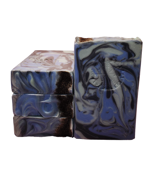 Four bars of Valkyrie soap. The bars contain swirls of blue, dark blue, and gray and are topped with Icelandic black sand. The bars are stamped with the Vegvisir stave, also known as the Viking Compass.