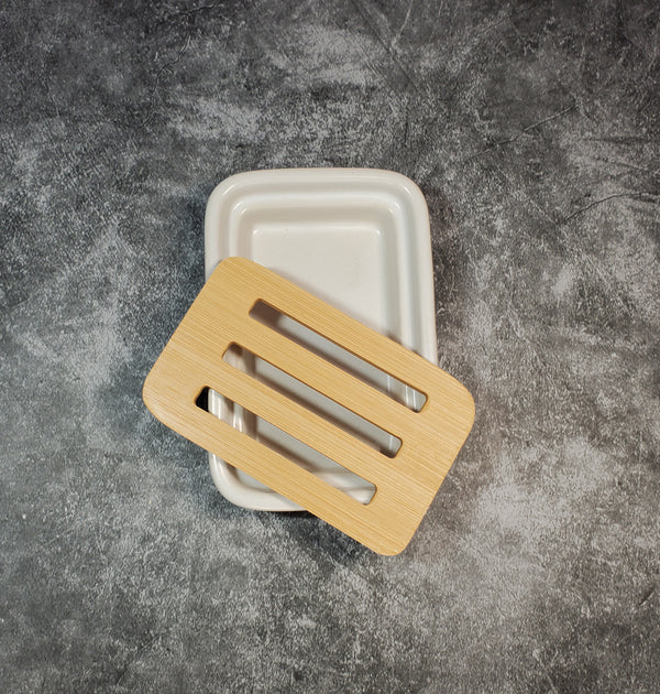 A white, rectangular ceramic dish accompanied by a bamboo slotted tray. The background is gray.