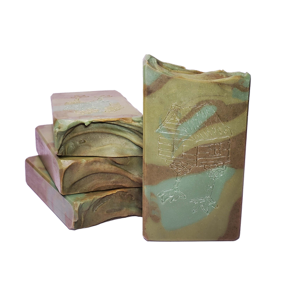 Four bars of Baba Yaga soap. Each bar contains swirls of three different shades of green. Carved into each bar is an image of a small house standing on chicken legs.