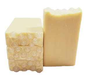 Four bars of Champagne soap. Each bar is light yellow with glitter swirls, and the bars are topped with clear soap balls and glitter.