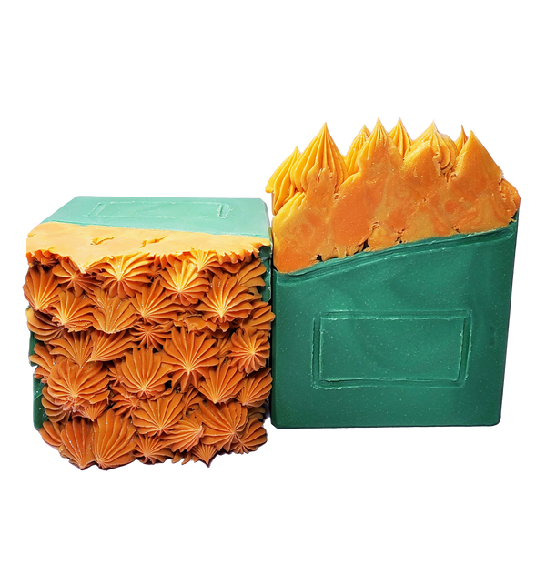 Two bars of Dumpster Fire soap. The soap bars look like a side view of a green dumpster with glittery orange flames coming out of the top.