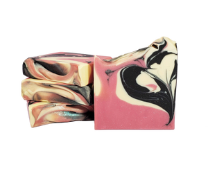 Four bars of The Lovers soap. The bars are pink with swirls of black and white. There is glitter throughout the bars and sprinkled on top. One bar features black and white swirls in the shape of a heart.