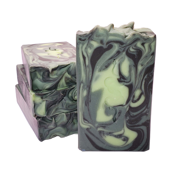 Four bars of Medusa soap. The bars contain swirls of light green, shimmery dark green, and black. A design of two entwined snakes is stamped on each bar.