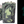 Load image into Gallery viewer, One bar of Medusa soap shown both in the light and in the dark. The bar contains swirls of light green, shimmery dark green, and black. A design of two entwined snakes is stamped on each bar. The photo of the soap bar in the dark demonstrates that the light green swirls glow in the dark.
