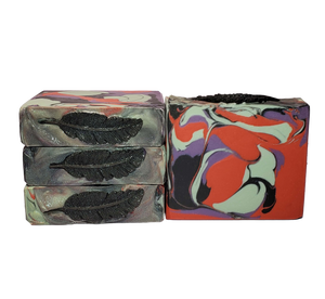 Four bars of The Morrigan soap. Each bar contains red, light green, purple, and black swirls and is topped with a black soap feather and glitter.
