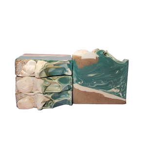 Four bars of Siren soap. The bars look like a beach scene, with a shore and waves. The tops of the bars also look like a shore, with soap shells, salt, and a wave pattern.