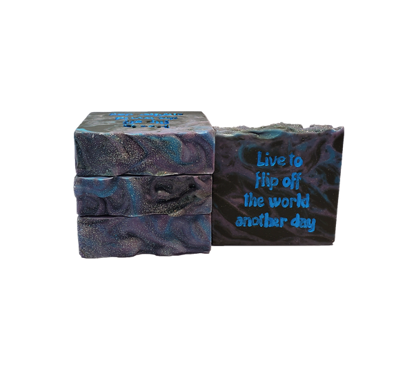 Four bars of Space Mom soap. Each bar contains black, blue, and purple swirls and is topped with glitter. The bar face reads "Live to flip off the world another day."