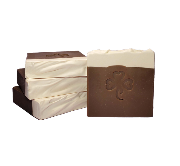 Four bars of Whisky & Oatmeal Stout soap. Each bar is dark brown with a creamy top and is stamped with a shamrock.